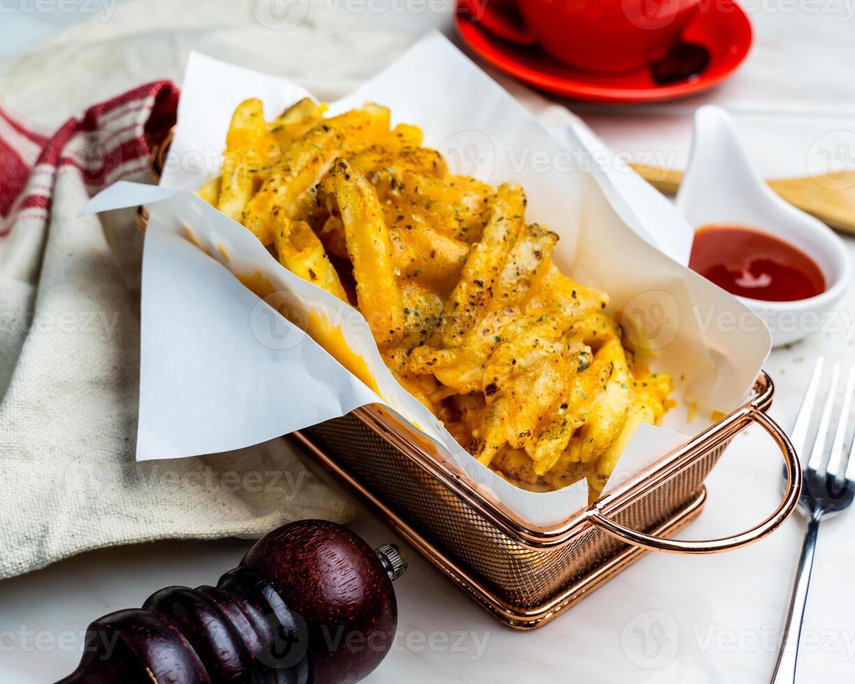 Spicy cheese baked fries served in bucket with ketchup isolated on napkin side view of fastfood on table photo