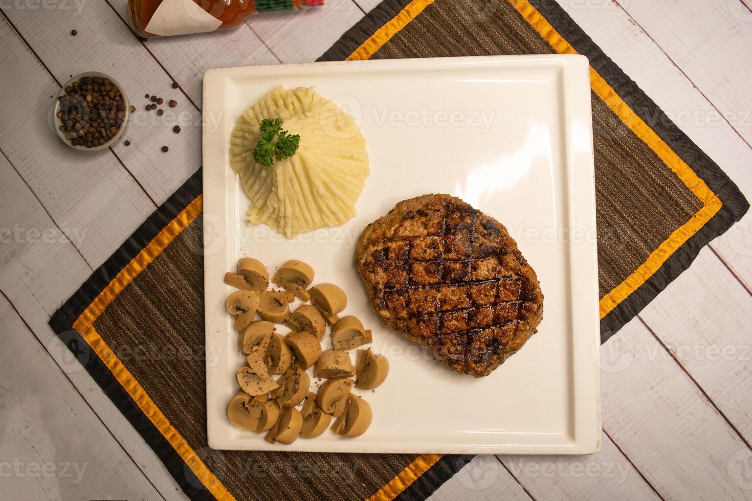 Signature Grilled Rib Eye Beef Steak with mushroom, dip, black pepper and garlic chilli sauce served in dish isolated on napkin top view on wooden table italian food photo