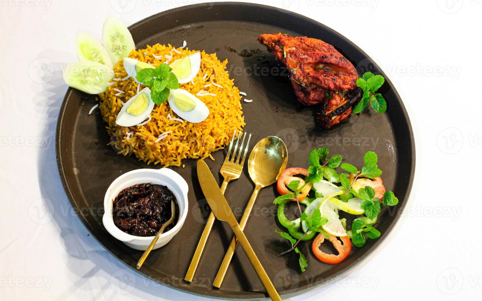 Grilled Chicken tikka biryani rice with egg, salad, spoon, fork and knife served in dish isolated on table top view of indian spices food photo