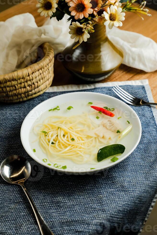 Clear Lemon Chicken Wonton include noodles, spring onion and red pepper served in bowl isolated on napkin side view of chinese soup photo