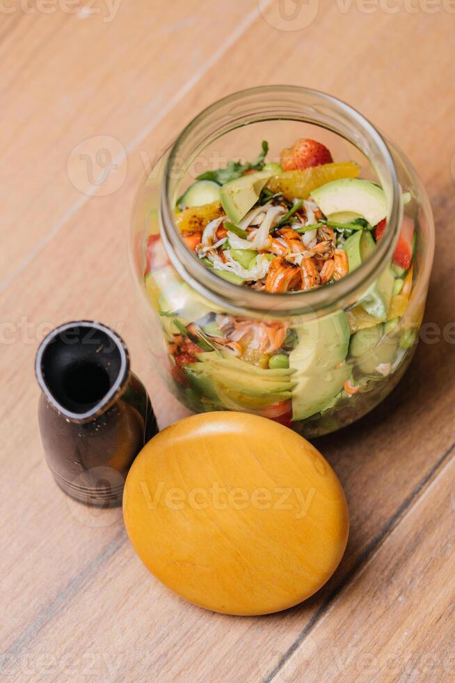 temblando ensalada en tarro o masón ensalada tarro con fresa, pepino, tomate, Zanahoria y lechuga hoja servido en plato aislado en mesa lado ver de sano orgánico ensalada foto