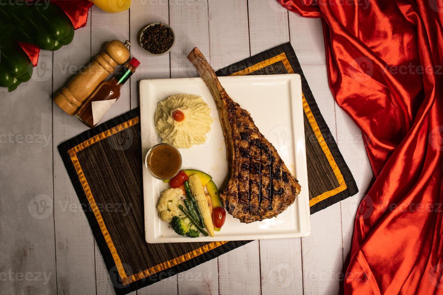 Signature tomahawk Bone Steak with black pepper, sauce and salad served in dish isolated on napkin top view on wooden table italian food photo