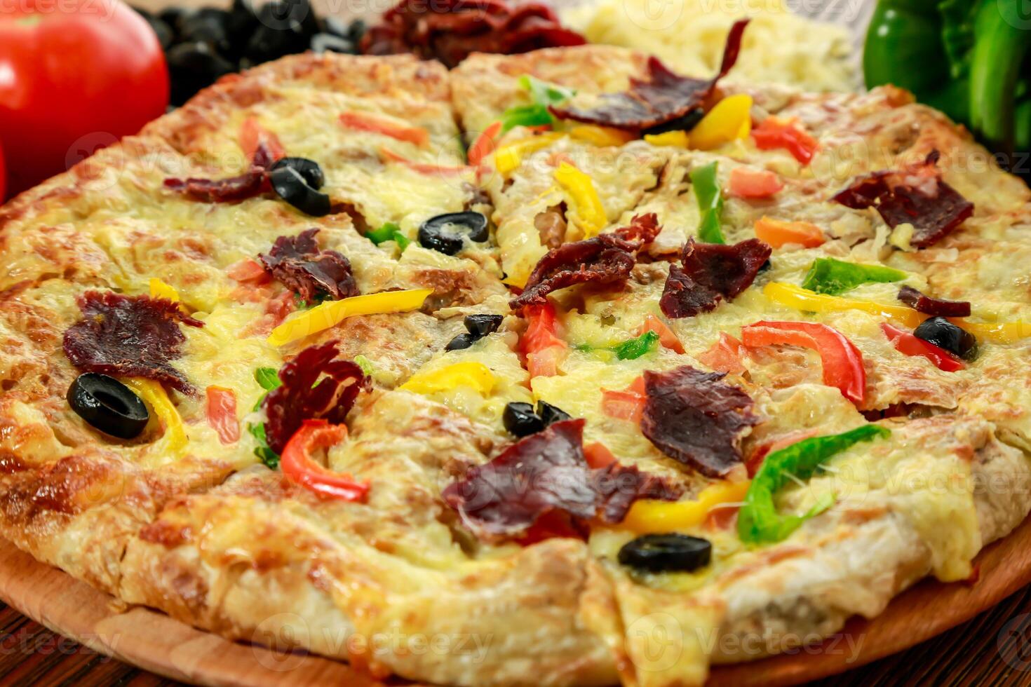 Pastrami and eggs pizza pie with bell pepper, tomato and black olive served in wooden board isolated on table side view of arabic food photo