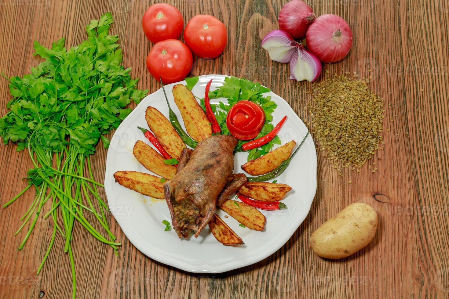 Stuffed pigeon with potato veggies, tomato, onion and coriander served in dish isolated on wooden table top view of arabic food photo