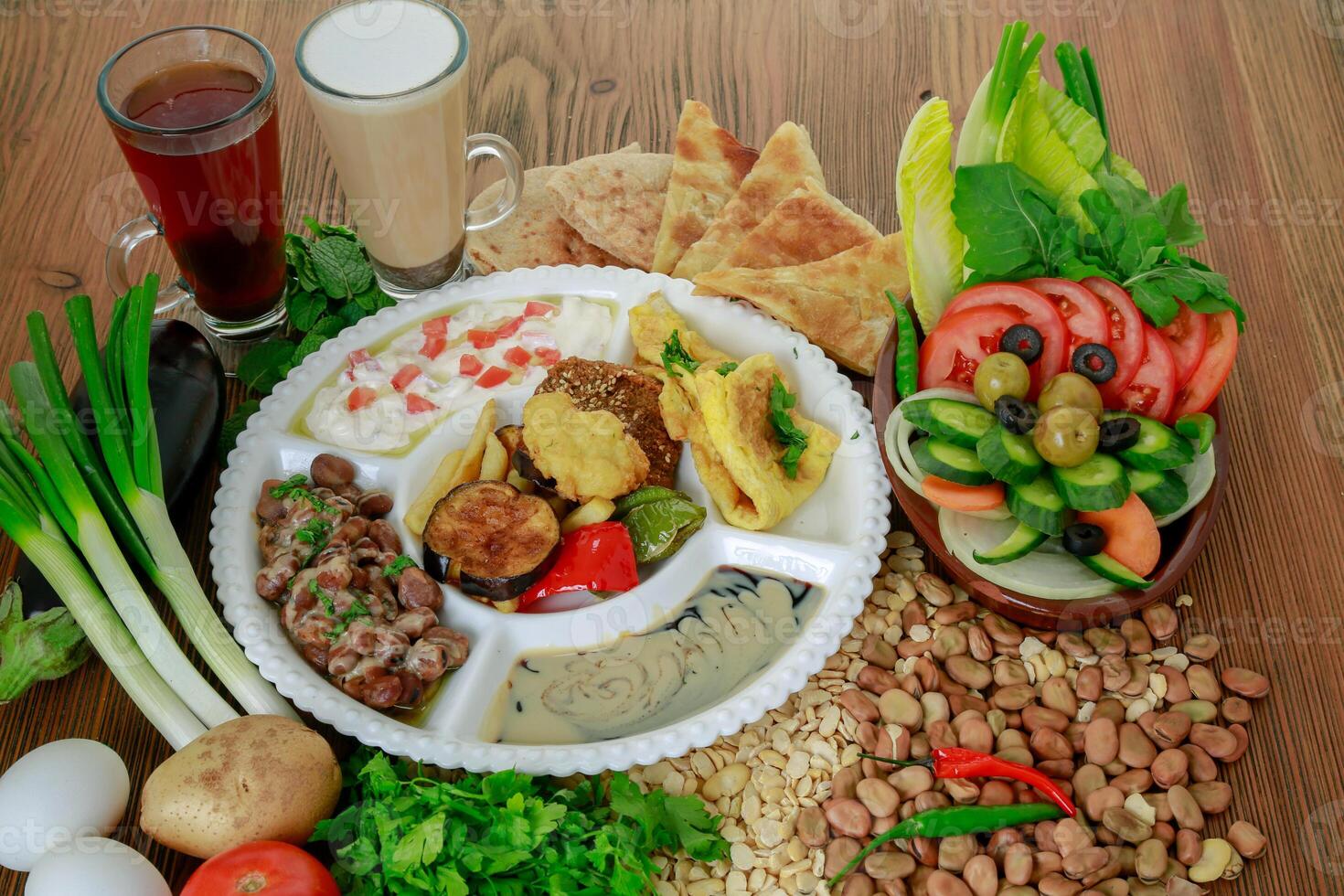 Egyptian Dynamite breakfast platter with flafel, marinated fried eggplant, omelette, hummus, foul, beans, pita bread, salad and coffee drink isolated on table side view photo