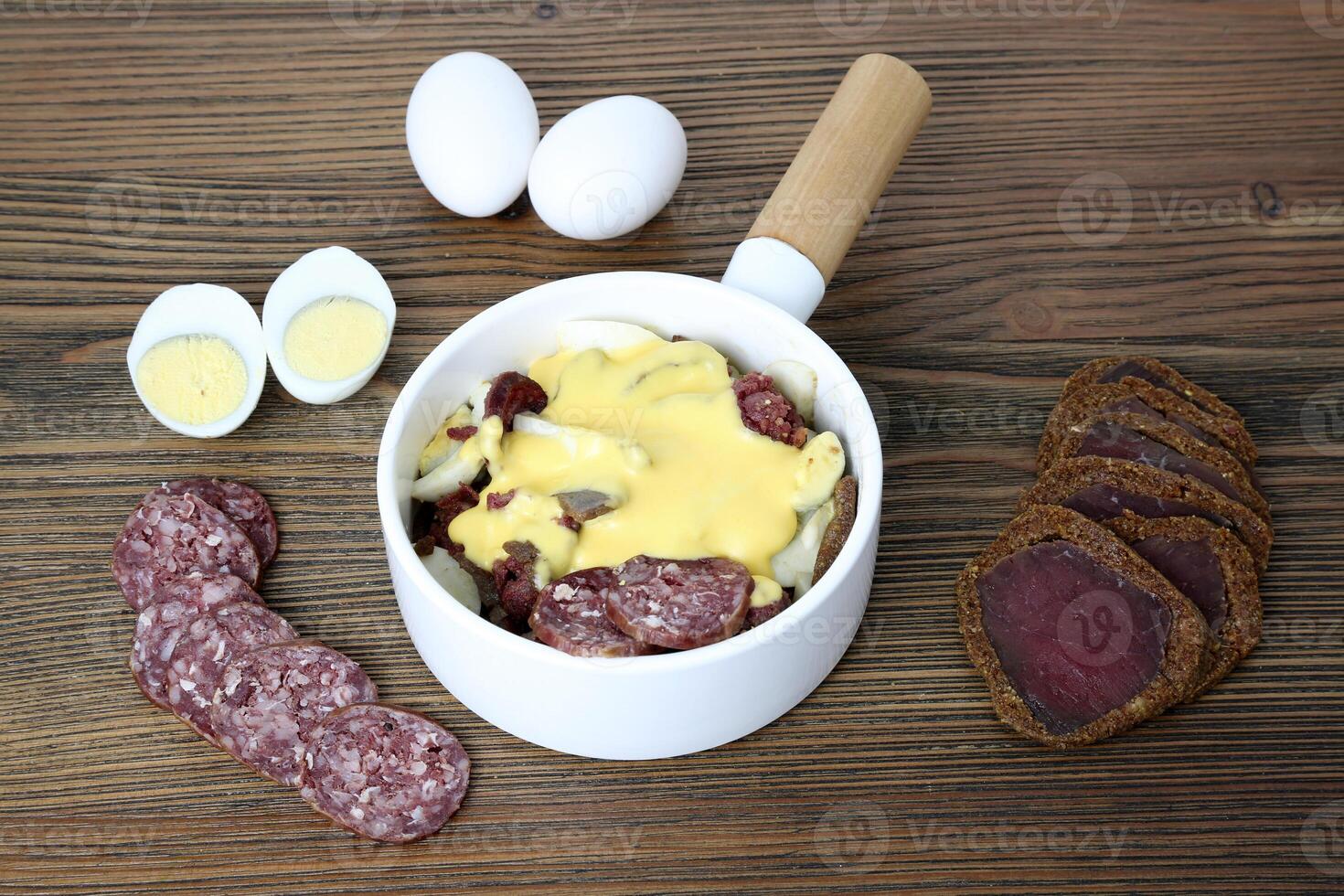 smoked salami with boiled eggs and cheese served in dish isolated on wooden table side view of arabic food photo