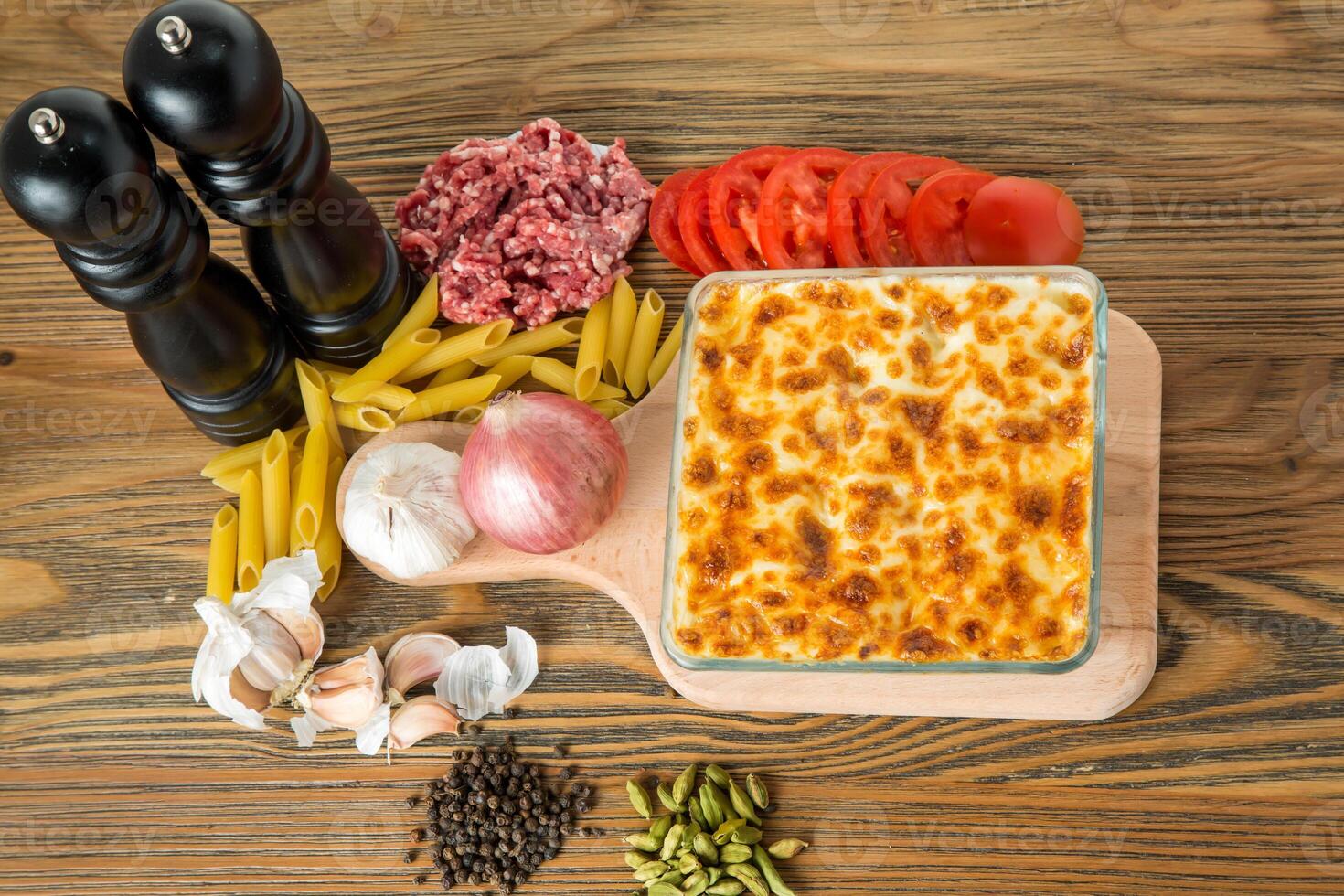 Pasta bechamel oven baked served in dish with minced meat, tomato, garlic, onion, black pepper and cardamom isolated on table top view of arabic food photo