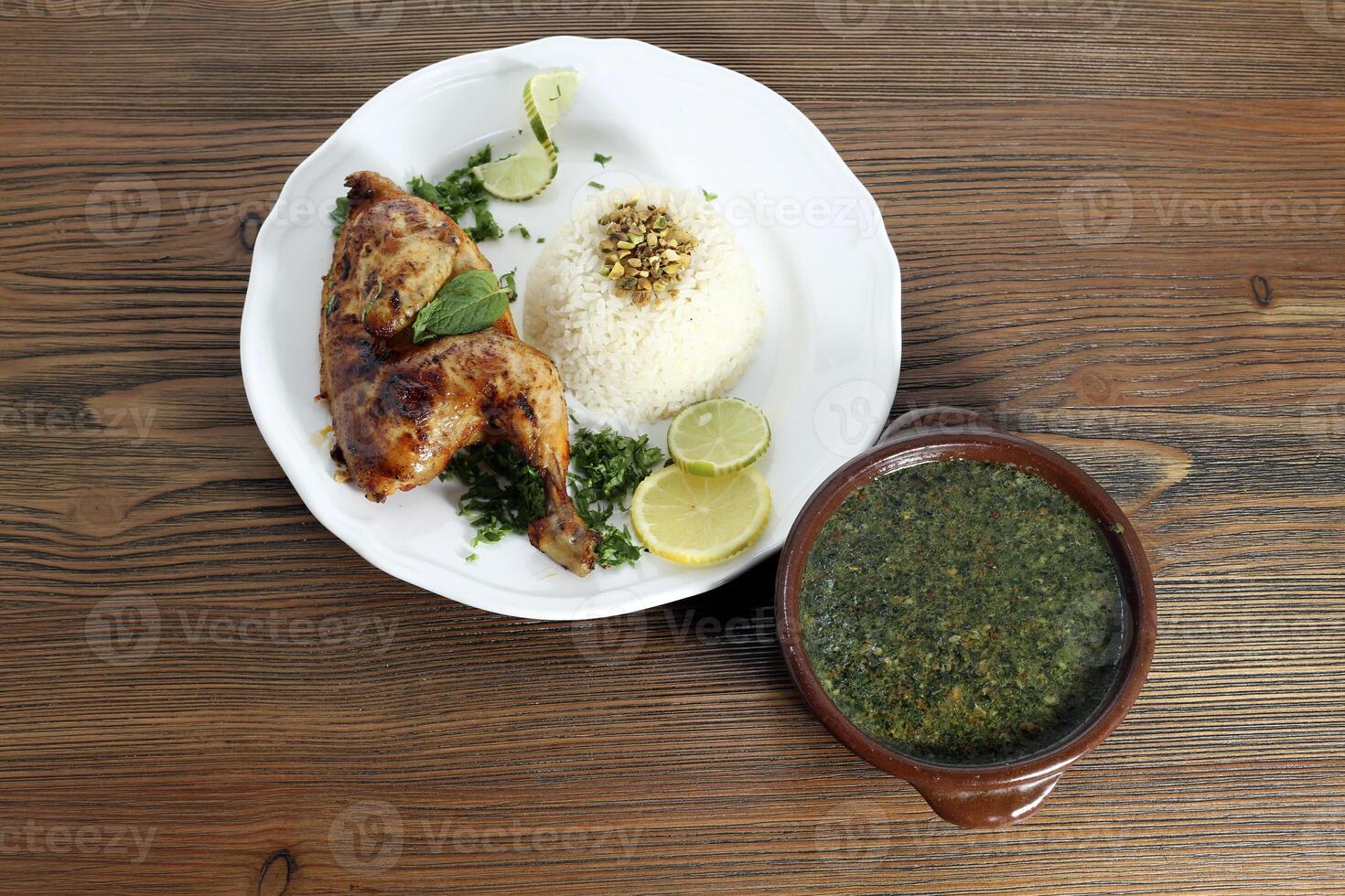 Molokhiya with grilled chicken and boiled rice served in dish isolated on table top view of arabic food photo