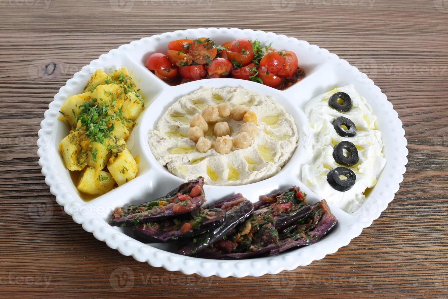 mezcla ensaladas con hummus, Cereza tomate, papa, aceituna, garbanzos y carne plato servido en plato aislado en mesa lado ver de Arábica comida foto