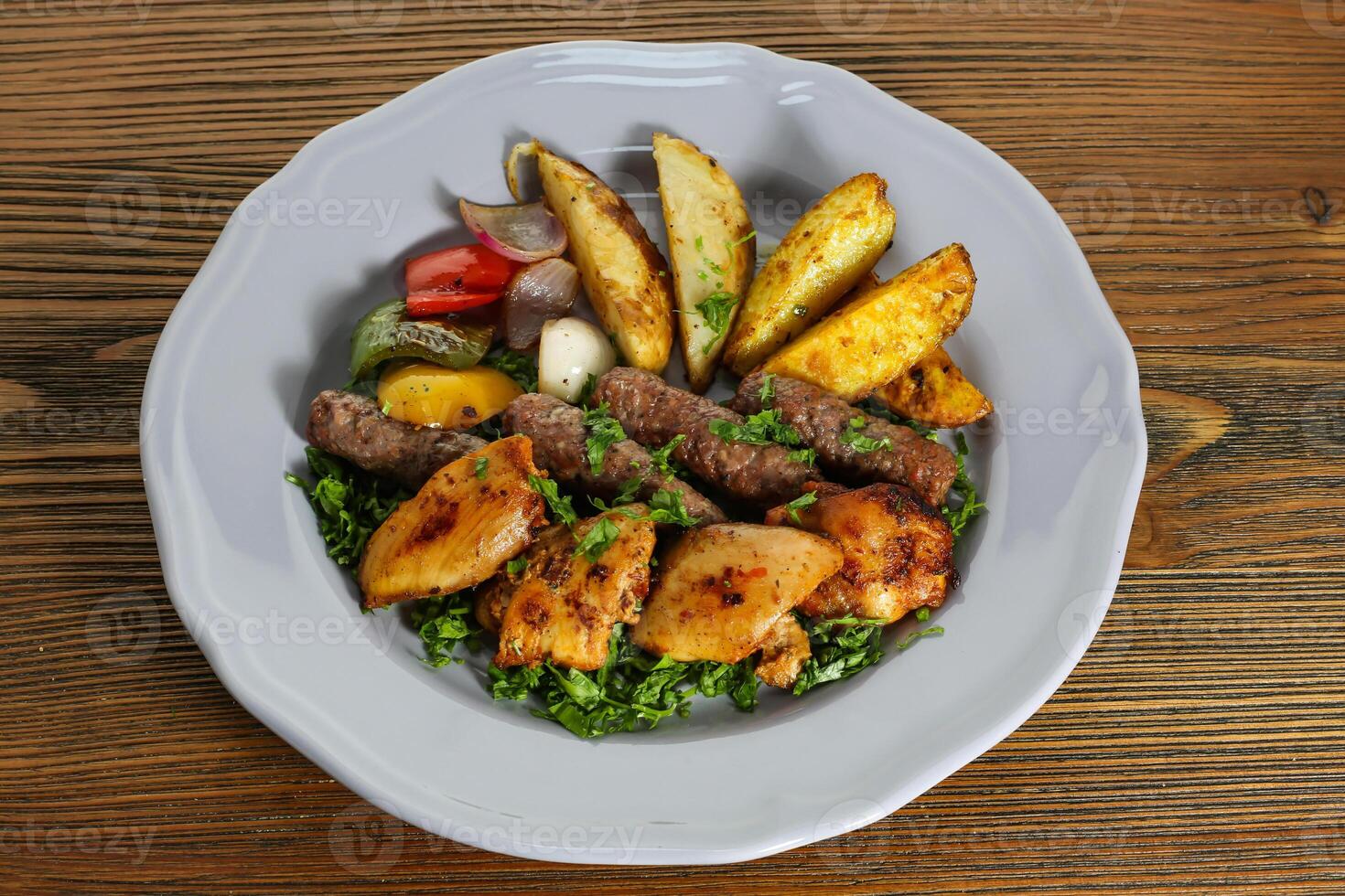 Mix kofta and shish tawook kabab with potato veggies, tomato, onion and coriander served in dish isolated on table side view of arabic food photo