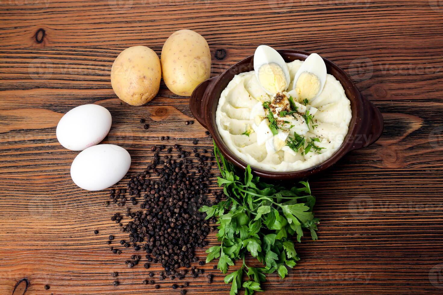 Mashed potatoes with boiled eggs coriander and black pepper served in dish isolated on table top view of arabian food photo