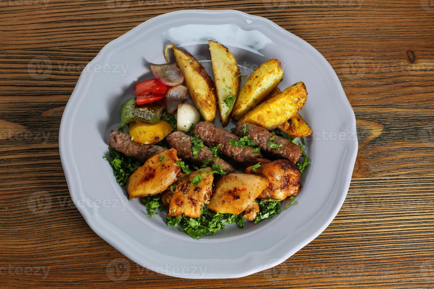 Mix kofta and shish tawook kabab with potato veggies, tomato, onion and coriander served in dish isolated on table top view of arabic food photo