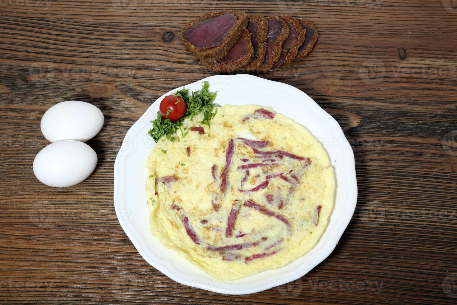 Pastrami omelette with smoked meat served in dish isolated on wooden table top view of arabic food photo