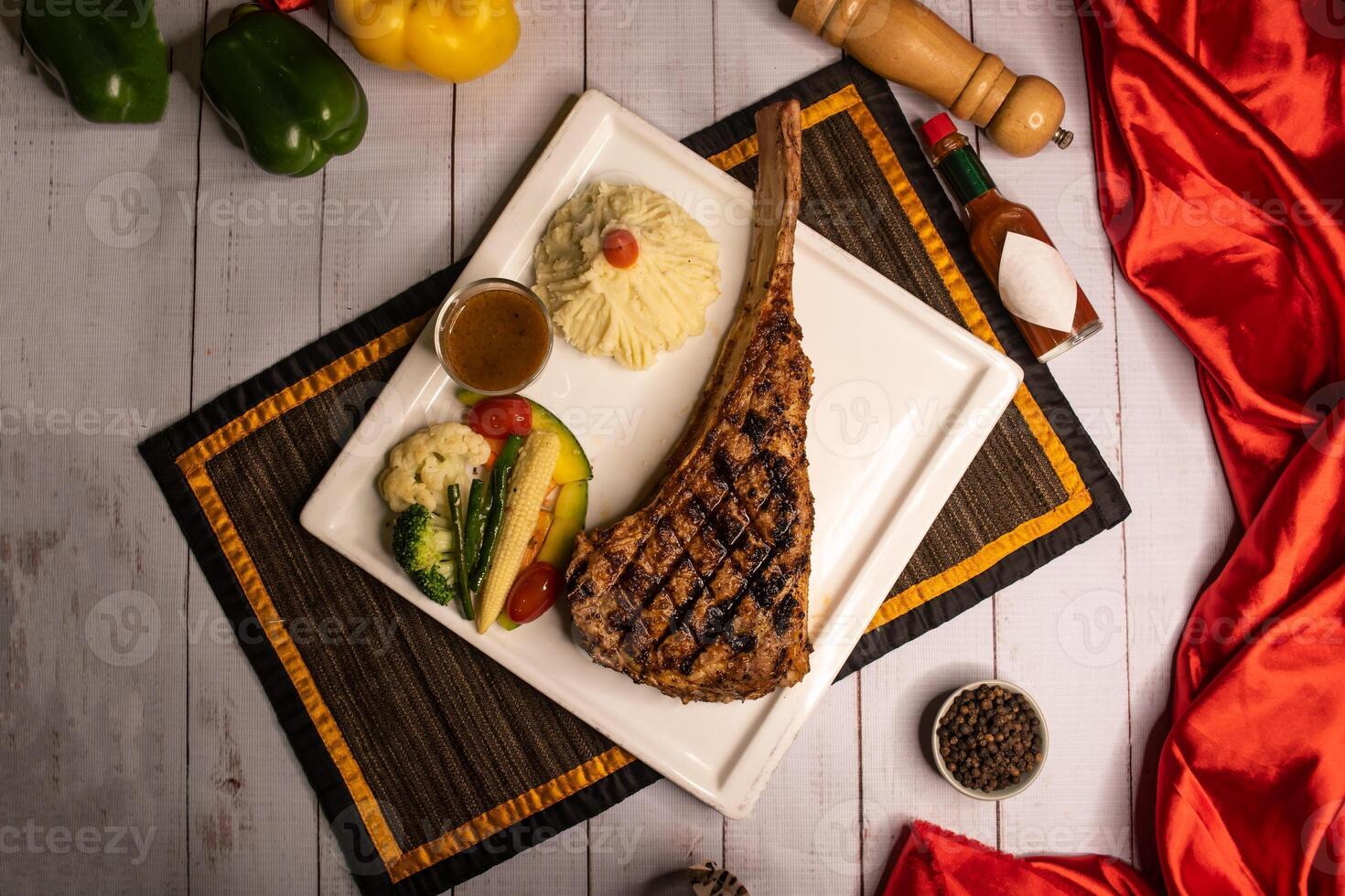 Signature tomahawk Bone Steak with black pepper, sauce and salad served in dish isolated on napkin closeup top view on wooden table italian food photo