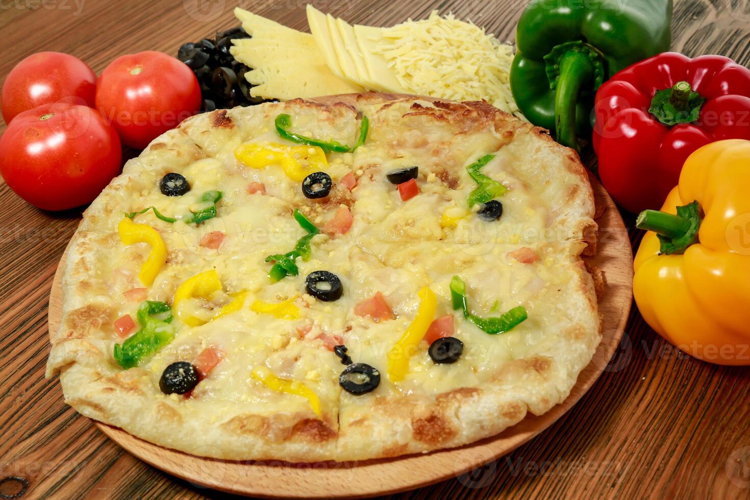 Mix cheese and vegetable pizza with bell pepper, tomato and black olive served in wooden board isolated on table side view of arabic food photo