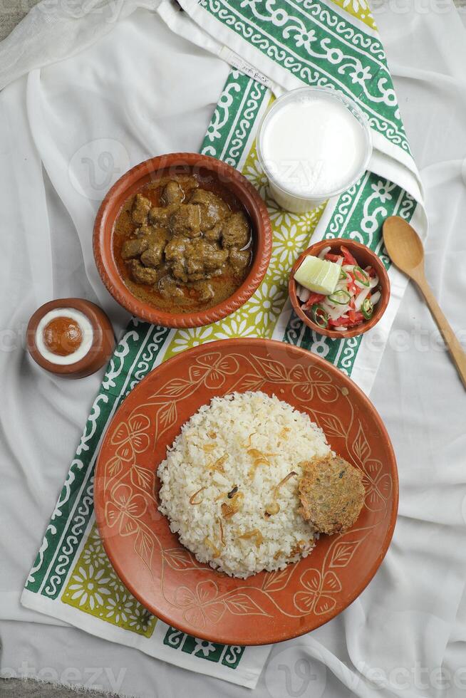 Mezbani Beef korma karahi khichuri rice Combo with salad, borhani and baked gulab jamun served in dish isolated on mat top view of indian and bangladeshi food photo