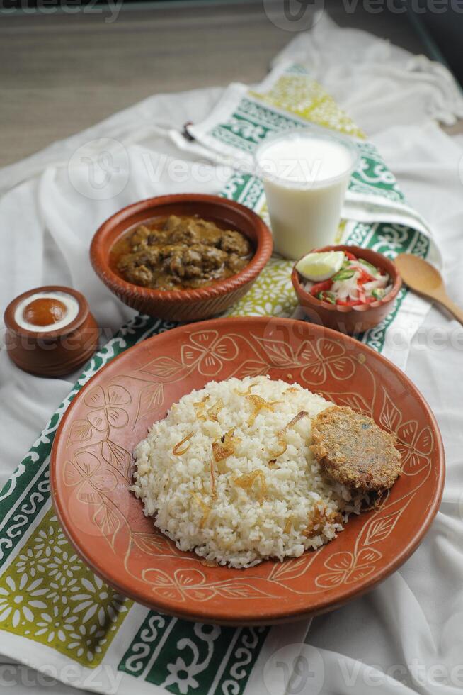 Mezbani Beef korma karahi khichuri rice Combo with salad, borhani and baked gulab jamun served in dish isolated on mat top view of indian and bangladeshi food photo