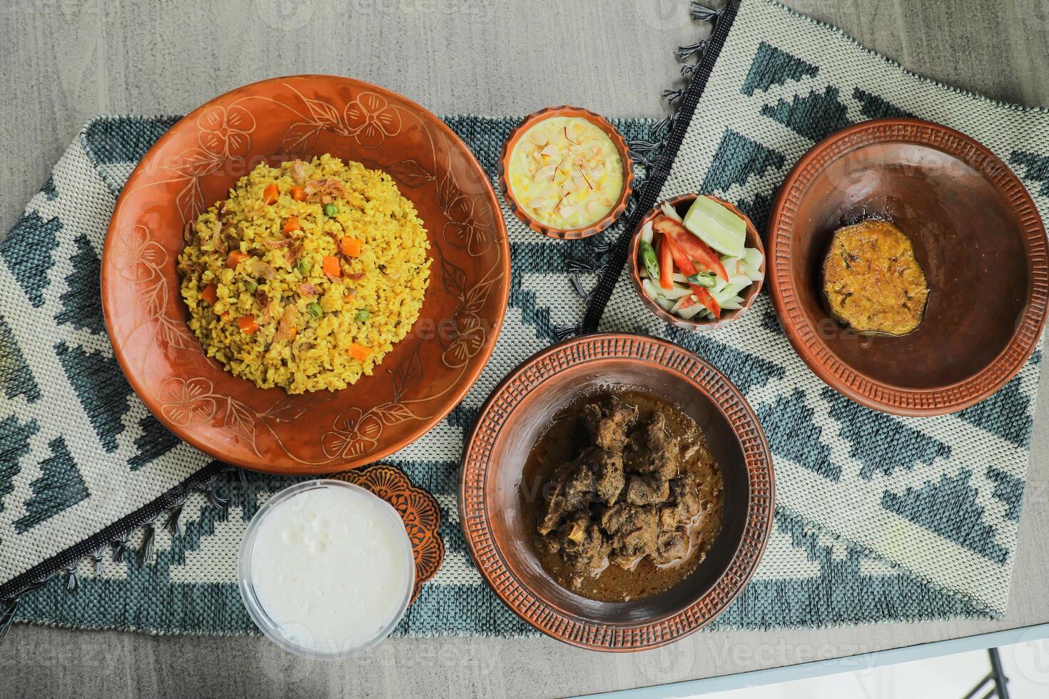 Haash Bhuna Khichuri Combo with egg plant, korma karahi, meat, salad, borhani and firni served in dish isolated on mat top view of indian and bangladeshi food photo