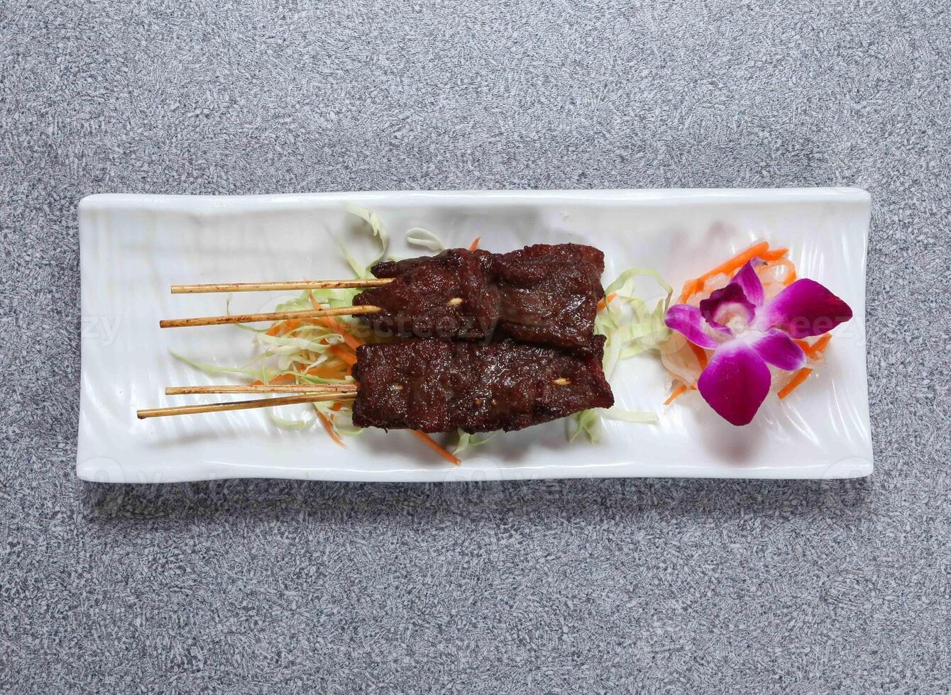 Beef satay sticks served in dish isolated on grey background top view of hong kong food photo