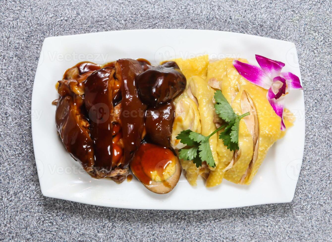 Braised Pork Trotter with hai nam chicken in thai style with sauce served in dish isolated on grey background top view of hong kong food photo