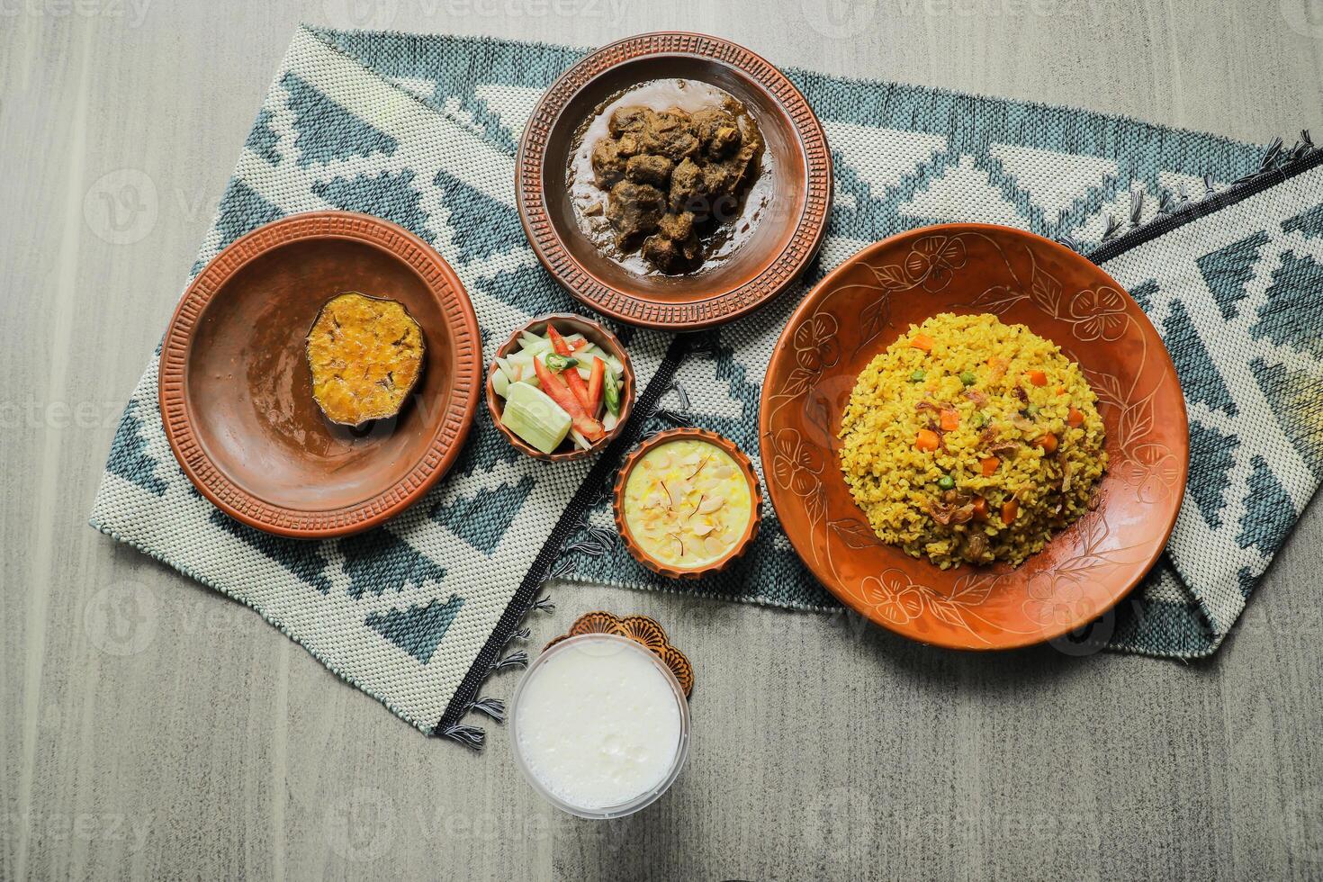 Haash Bhuna Khichuri Combo with egg plant, korma karahi, meat, salad, borhani and firni served in dish isolated on mat top view of indian and bangladeshi food photo