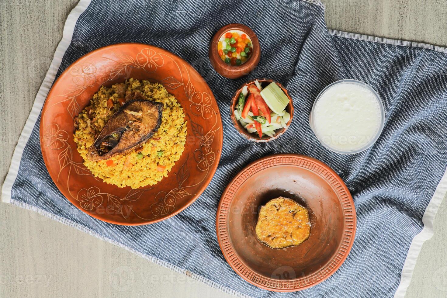 Hilsa Khichuri Combo with salad, eggplant, borhani and boondi rabi served in dish isolated on mat top view of indian and bangladeshi food photo