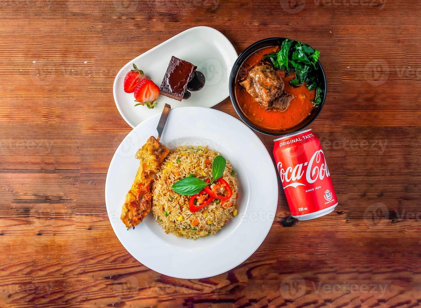 garlic fried rice with skewer, chicken satay, brownie and coke can 330 ml served in dish isolated on wooden table top view of hong kong food photo