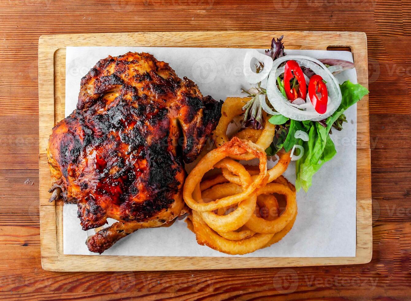 whole grilled chicken with onion rings and salad served wooden board isolated on wooden table top view of hong kong food photo