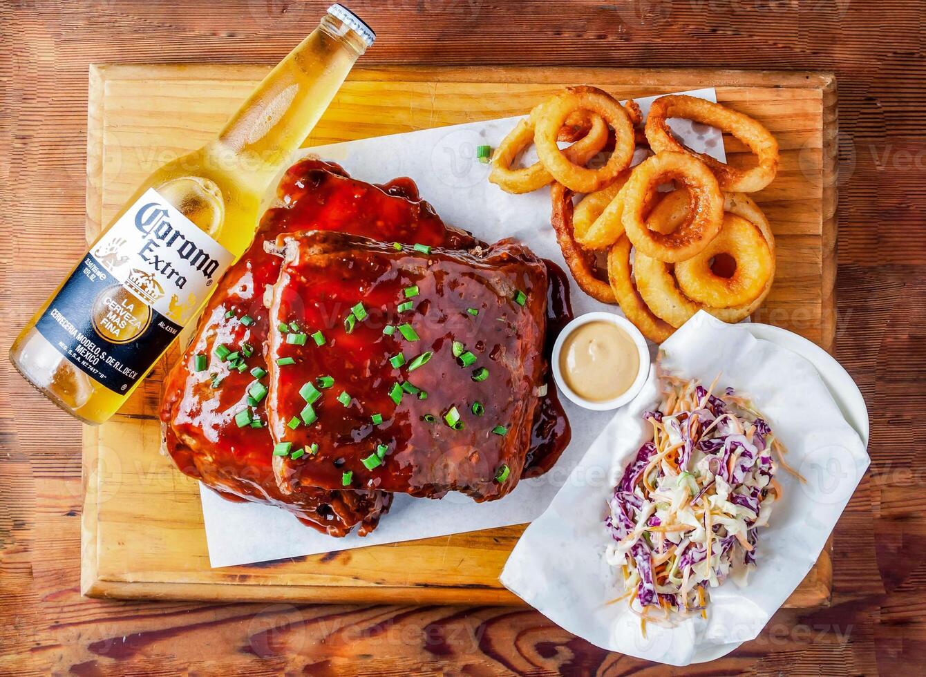 US baby back ribs with onion rings, salad, corona extra beer 335 ml and mayonnaise dip served in dish isolated on wooden table top view of hong kong food photo
