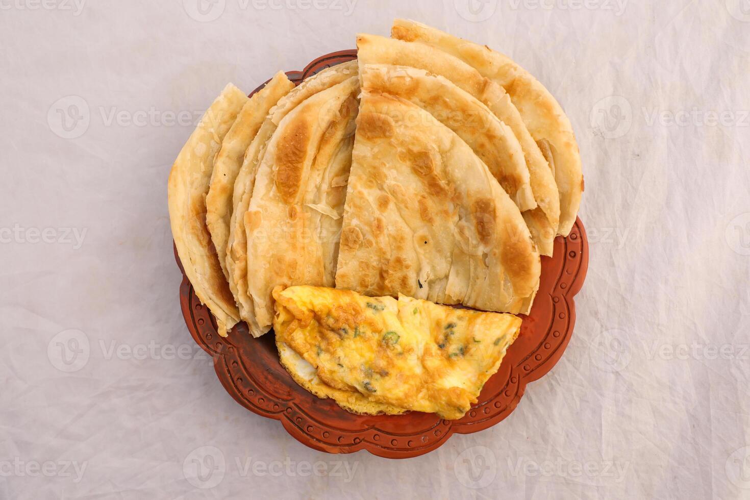 desi breakfast egg omelet and paratha served in dish isolated on background top view of bangladesi breakfast photo