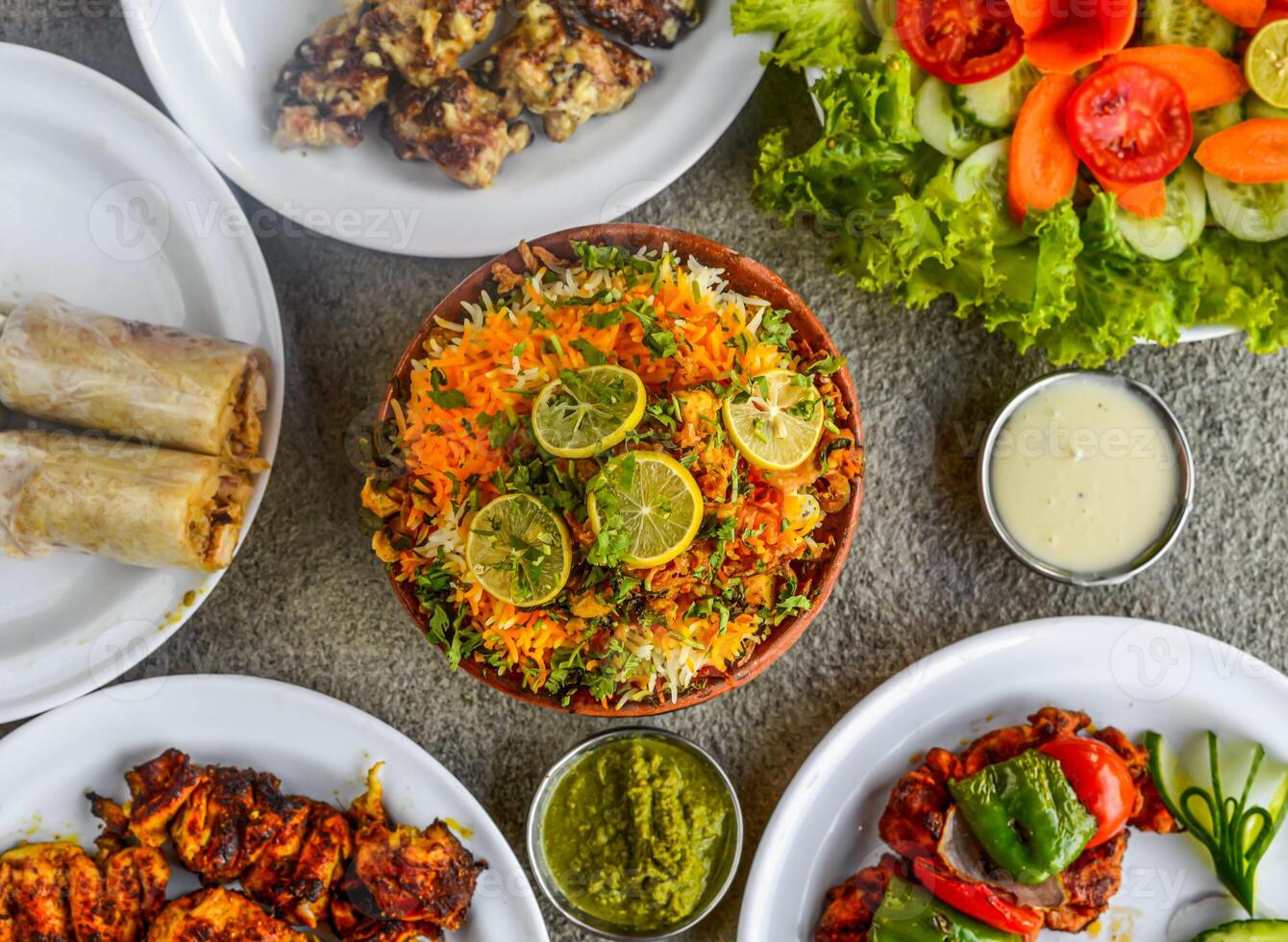 matka Biryani o arcilla Biryani mano, pollo rollo, malai bota tikka kebab, Fresco verde ensalada, mayonesa inmersión y chatney aislado en antecedentes parte superior ver de clasificado indio especias y pakistaní comida foto