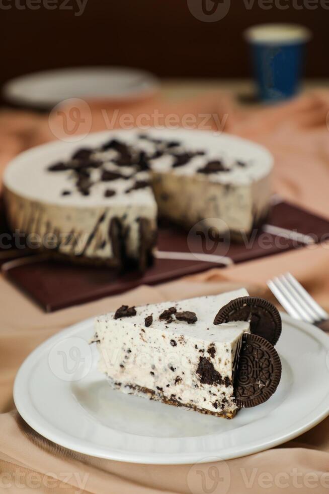 Oreo Cheesecake slice include chocolate, cream, sugar with fork and flowers served in plate isolated on napkin side view of cafe food photo