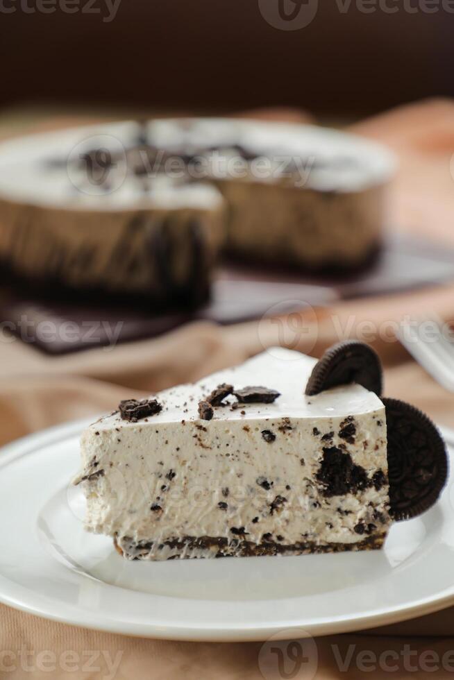 Oreo Cheesecake slice include chocolate, cream, sugar with fork and flowers served in plate isolated on napkin side view of cafe food photo