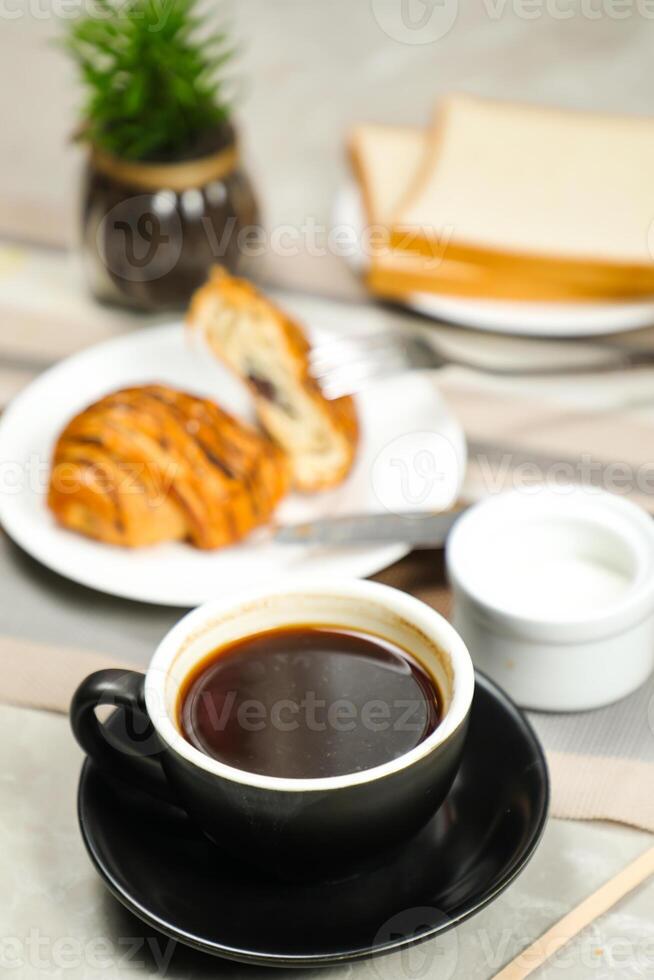 Americano coffee served in cup with croissant, puff pastry, bread and knife isolated on napkin side view cafe breakfast photo