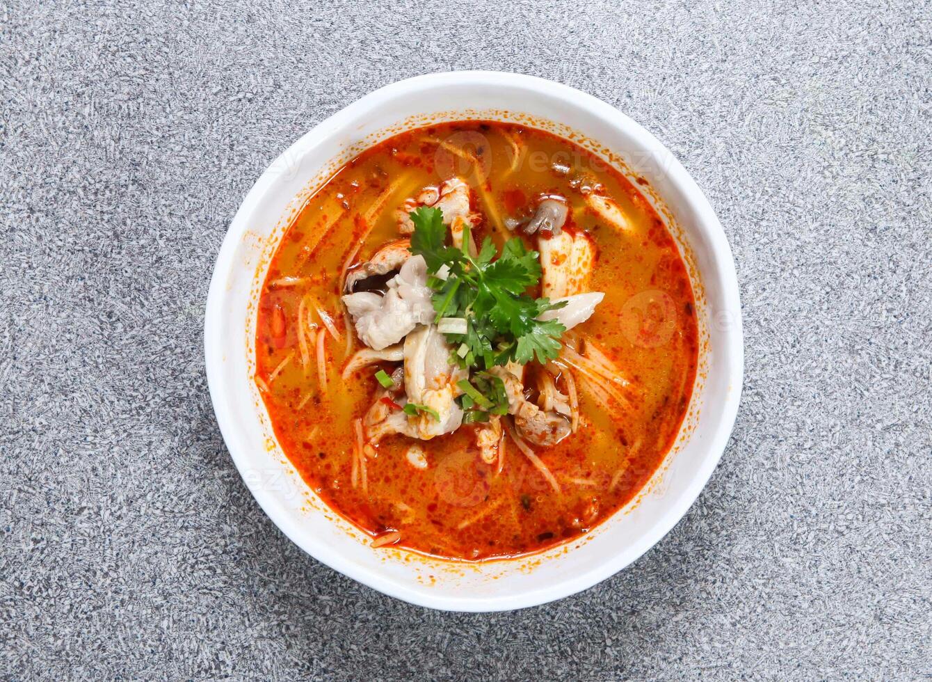 thai rice noodle in tom yum chicken soup served in bowl isolated on grey background top view of hong kong food photo