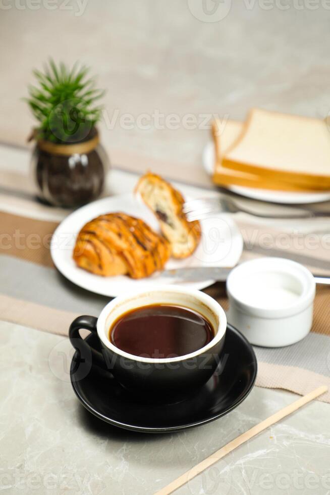 Americano coffee served in cup with croissant, puff pastry, bread and knife isolated on napkin side view cafe breakfast photo