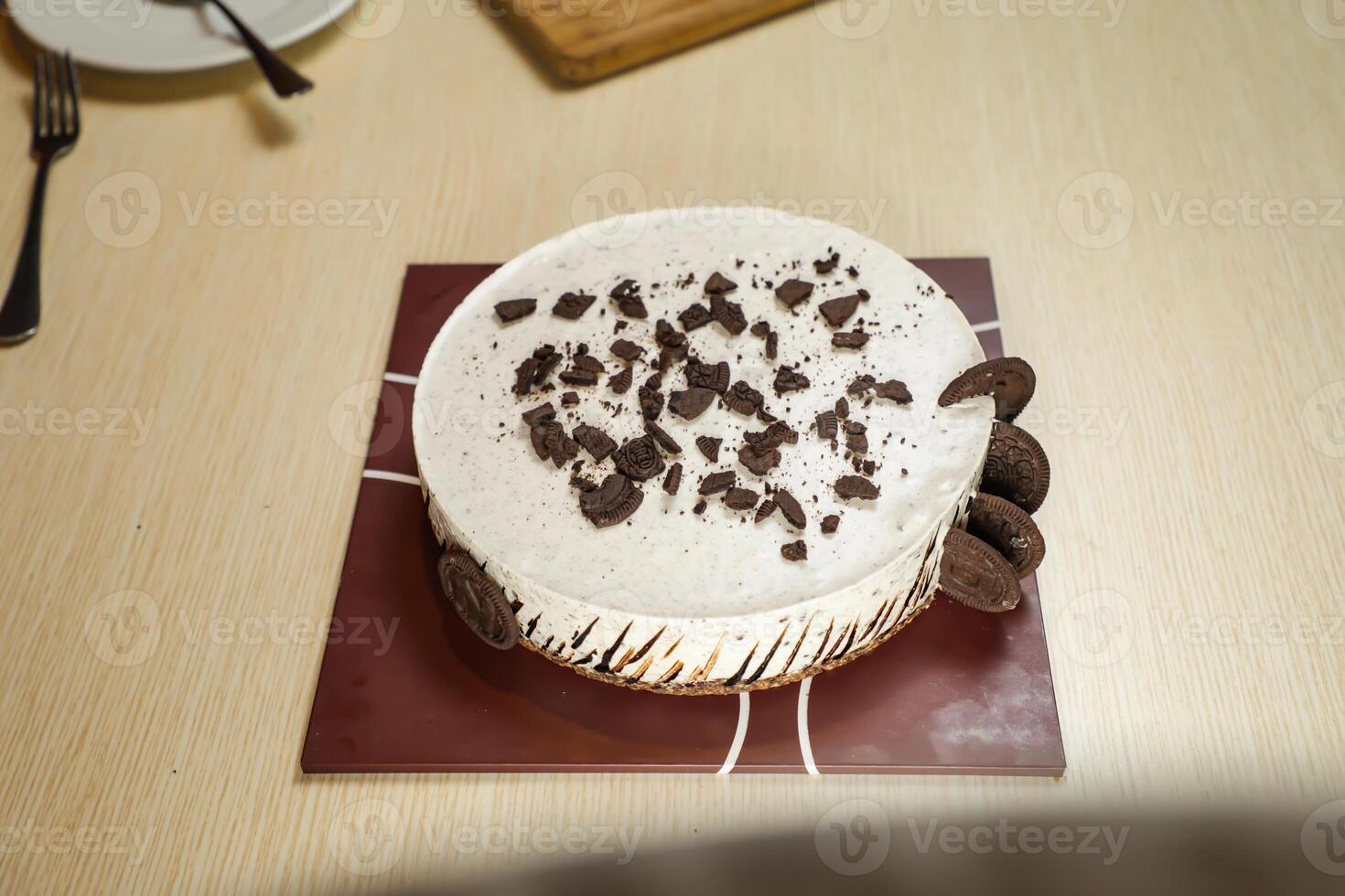 Oreo Cheesecake include chocolate, cream, sugar with fork and flowers served on board isolated on napkin side view of cafe food photo