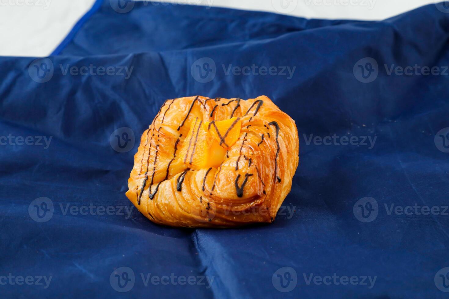 Peach Danish pastry puff isolated on blue napkin side view of french breakfast baked food item photo