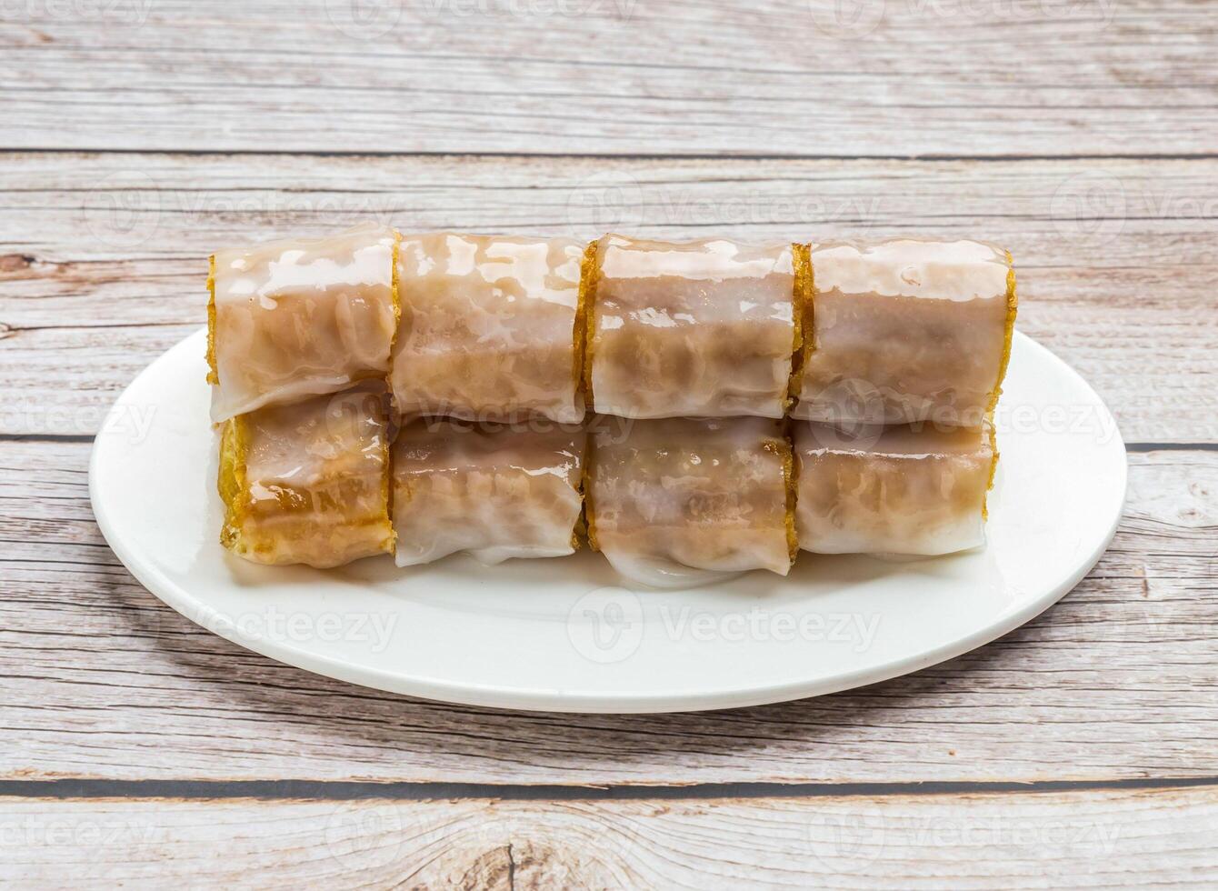 rice noodle rolls filled with twisted cruller served in dish isolated on wooden table top view hong kong food photo