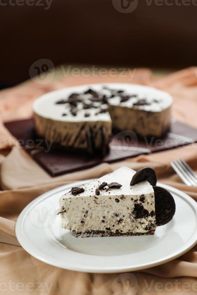 Oreo Cheesecake slice include chocolate, cream, sugar with fork and flowers served in plate isolated on napkin side view of cafe food photo