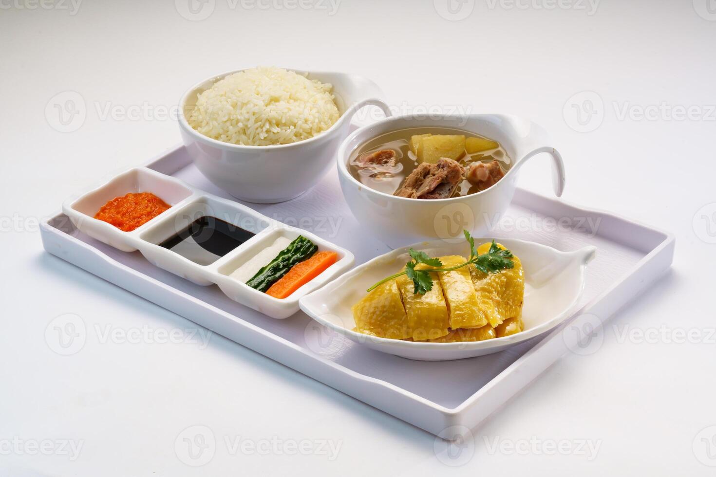 Boneless Hainanese Chicken Rice with chicken soup, soy sauce, chili sauce served in bowl isolated on wooden table side view of hong kong fast food photo