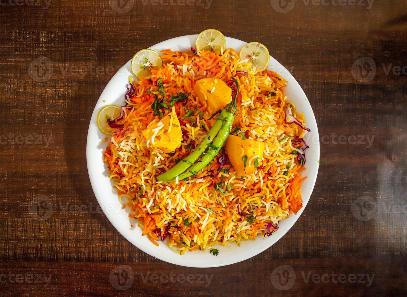 Aloo biryani rice with potato and lemon slice served in plate isolated wooden background top view indian spices and pakistani food photo