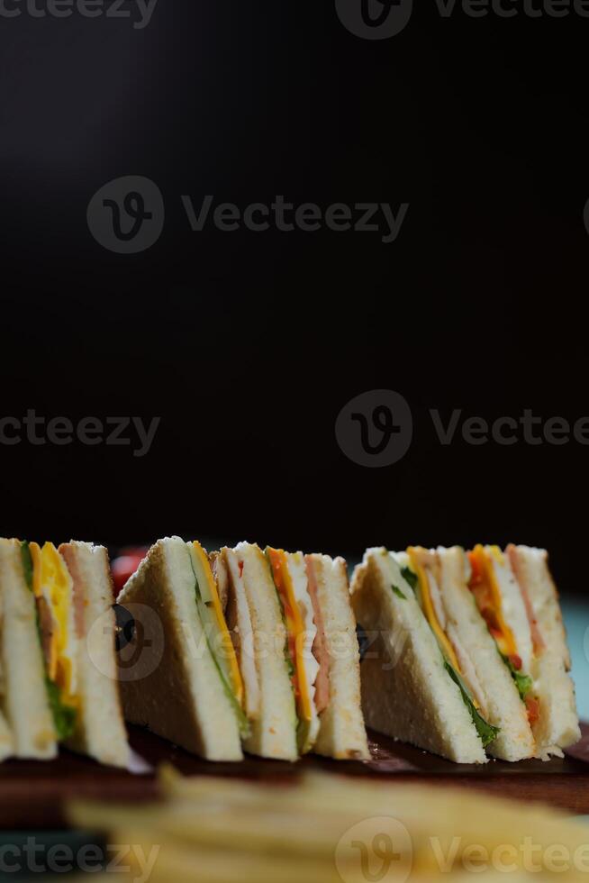 Assorted Club Sandwich isolated on wooden with mayonnaise dip and french fries bucket board side view of italian fast food on background photo