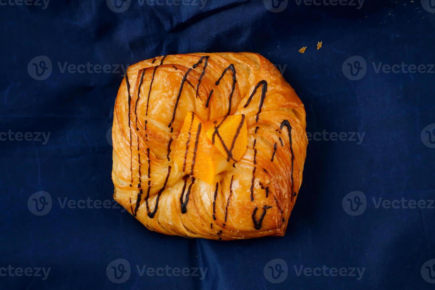 Peach Danish pastry puff isolated on blue napkin top view of french breakfast baked food item photo