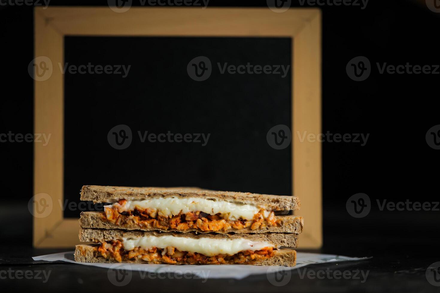 Chicken Tikka Mint Grilled Sandwich isolated on wooden board side view of fast food on dark background photo