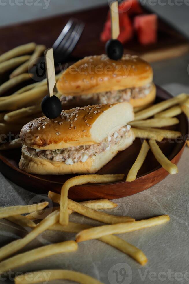 Tuna Egg Sandwich with fries and mayonnaise dip served in wooden board isolated on dark background side view of breakfast food photo