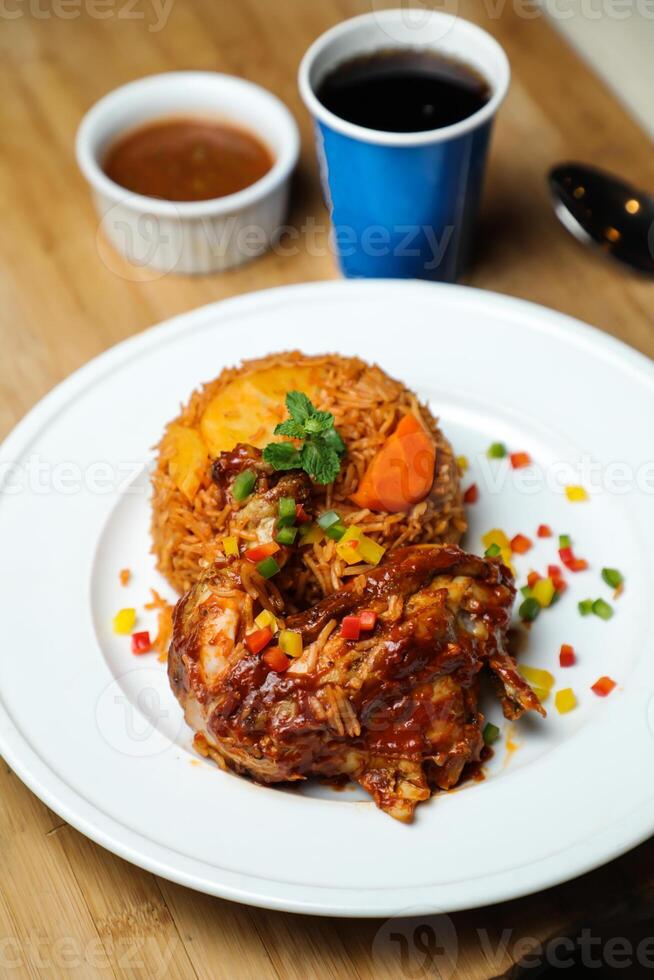 Chicken Majboos biryani rice pulao served in plate with sauce, cold drink, spoon and fork isolated on wooden board side view of arabic food photo