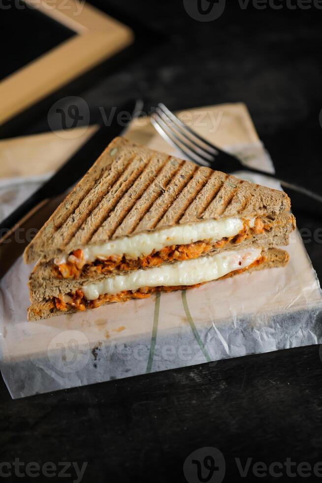Chicken Tikka Mint Grilled Sandwich isolated on wooden board side view of fast food on dark background photo