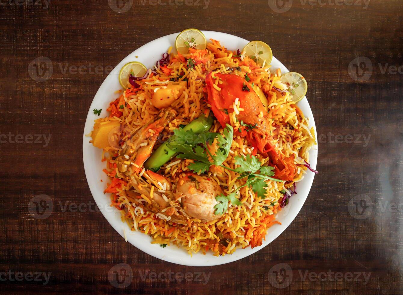 Spicy chicken biryani with potato and lemon slice served in plate isolated wooden background top view indian spices and pakistani food photo