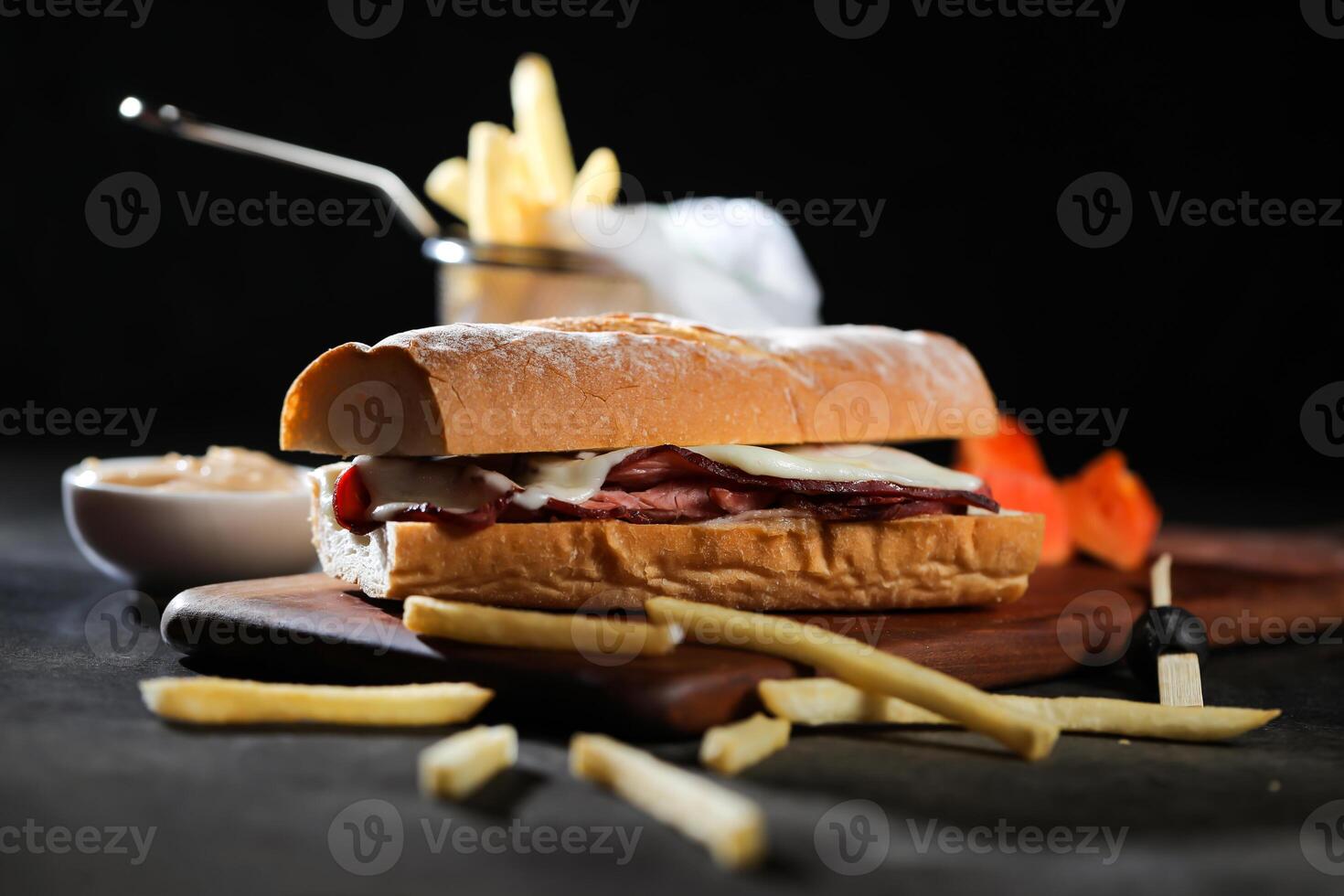 Roasted Beef Sub Sandwich with french fries bucket served on wooden board isolated on dark background side view of breakfast food photo